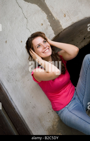 smiling pretty woman with brown curly hair, keeping her ears shut Stock Photo