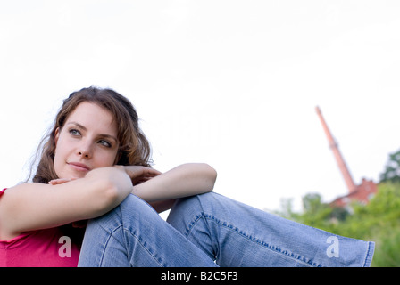 young woman with pink top sitting on a meadow Stock Photo