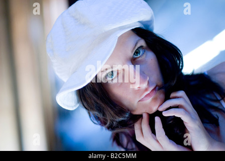 cute dark-haired woman with fashinable cap, with her hands on chin Stock Photo