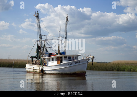 shrimp trawler heads out to sea along Scipio Creek near downtown Apalachicola Florida Stock Photo