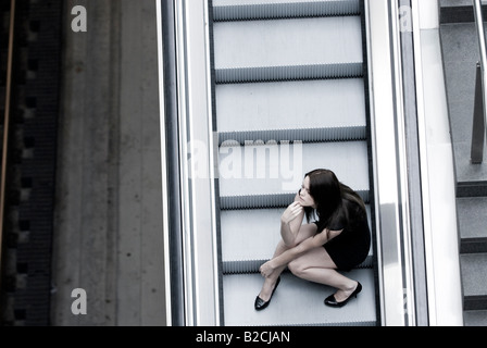 young woman sitting on broken escalator Stock Photo