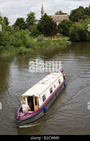 A woman sits on the bow of a canal boat on the Thames at Clifton Hampden Stock Photo