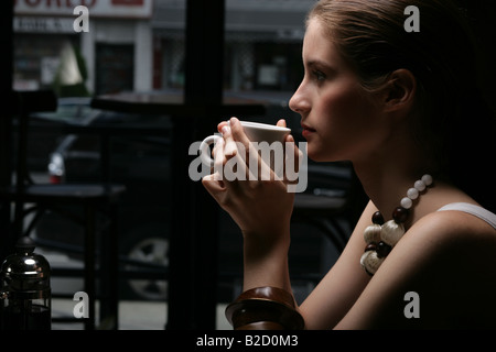 Young woman drinking coffee in café. Stock Photo