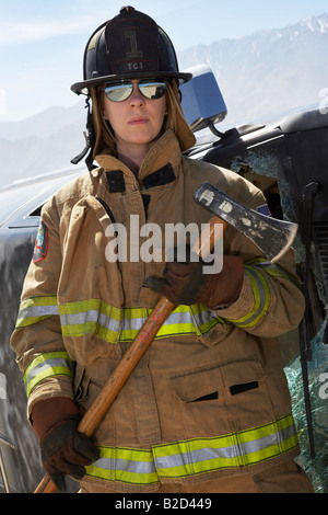Portrait of female firefighter holding axe Stock Photo