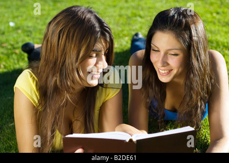 Two students lay on a grass with the book in a hand Stock Photo