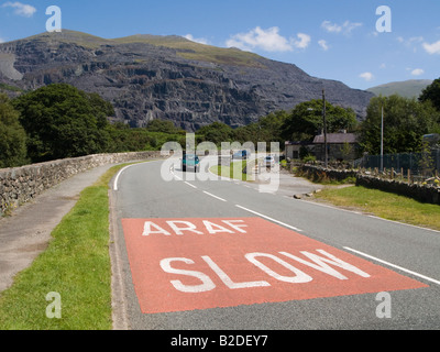 Bilingual Araf Slow sign in Welsh and English painted on a road surface before a bend near Llanberis Gwynedd North Wales UK Stock Photo