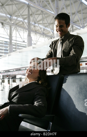 Young man giving businesswoman head massage in airport. Stock Photo