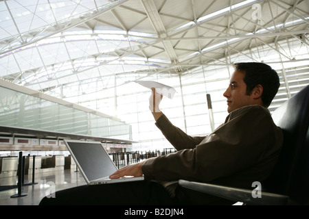 Young businessman throwing paper airplane in airport. Stock Photo