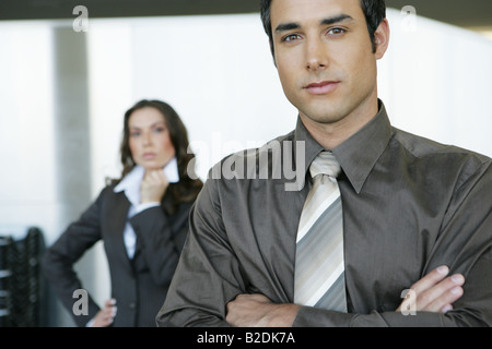 Portrait of businessman in airport with businesswoman behind. Stock Photo