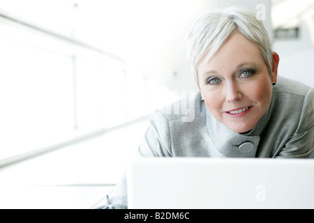Mature woman using laptop in airport. Stock Photo