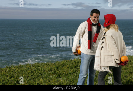 Young couple at coast holding pumpkins behind backs. Stock Photo