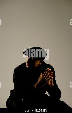 Young stylish African American man sitting, studio shot. Stock Photo