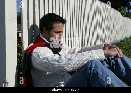 Young man sitting near fence. Stock Photo