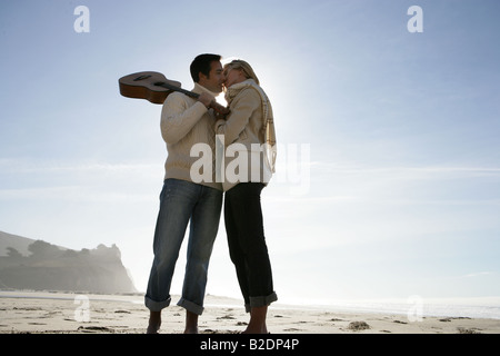 Young couple with guitar kissing on beach. Stock Photo