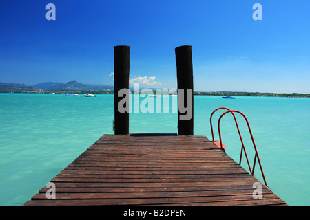 a small jetty in lake Garda Italy fantastic colors in sky and water Perfect for any sort of concept of vacations or tropics Stock Photo