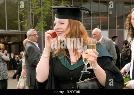 Happy smiling woman student after graduation talking on her mobile phone Aberystwyth University degree award day, Wales UK Stock Photo