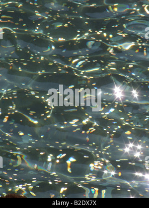 lots of sparkling coins in a wishing well water Stock Photo