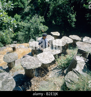 Beekeeper inspects beehives built with chestnut tree trunk and topped with Lauze stone Ardèche France Stock Photo