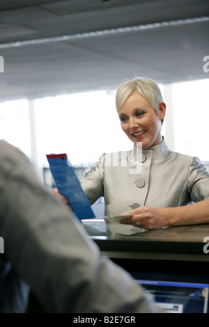 Mature woman checking in at airport. Stock Photo