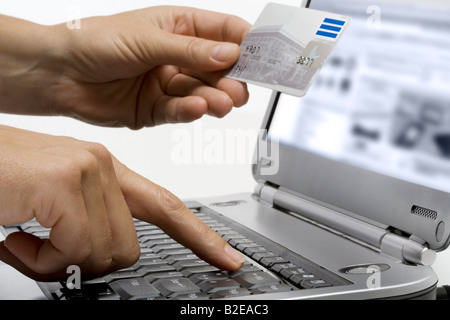 Close-up of person's hands holding credit card and using laptop Stock Photo