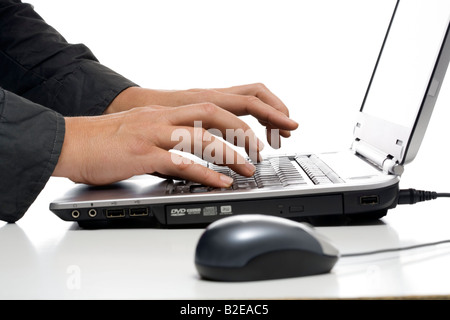 Close-up of computer mouse and person's hands using laptop Stock Photo