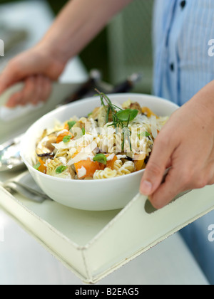 Mid section view of woman holding bowl of pasta salad on tray Stock Photo