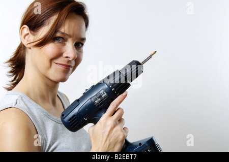 Portrait of woman holding electric drill and smiling Stock Photo