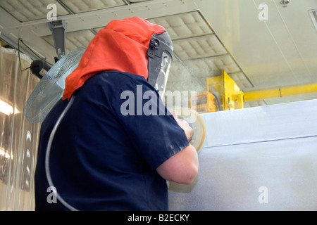 Worker wearing protective safety gear while using a power sander on fire truck chassis at Spartan Motors in Charlotte Michigan Stock Photo