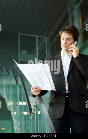 Businessman talking on a mobile phone and looking at a blueprint Stock Photo