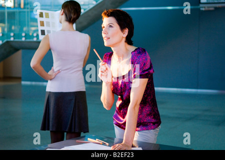 Mid adult woman making a blueprint with a young woman looking at a color swatch Stock Photo