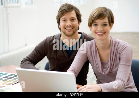 Portrait of a mid adult man and a young woman using a laptop Stock Photo