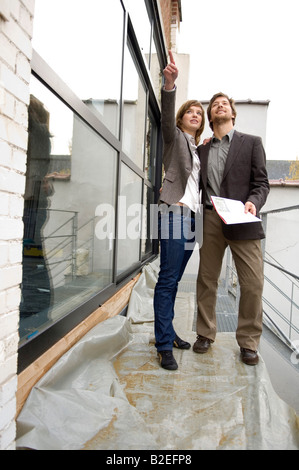 Young woman pointing forward and a mid adult man standing beside her Stock Photo