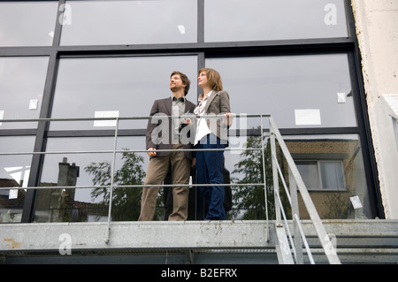Low angle view of a mid adult man and a young woman standing at a balcony Stock Photo