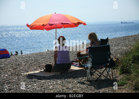 Two people sitting under a sun umbrella Stock Photo
