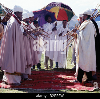 Ethiopian Orthodox priests perform the Dance of the Priests to celebrate Timkat (Epiphany), the church's most important Holy Day. Ethiopia is Africa's oldest Christian nation where more than half the population follows the Ethiopian Orthodox faith. During Timkat, priests stand in two rows, facing one another and sway gently as they chant. In addition to the staffs on their shoulders, they carry sistras, musical instruments, possibly of Egyptian origin, which have been used in religious ceremonies since Old Testament times. Attendants hold silk brocade umbrellas to shade them from the sun. Stock Photo