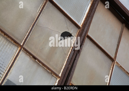 Rustic old windows and frames on an abandoned factory building with one broken glass pane. Stock Photo