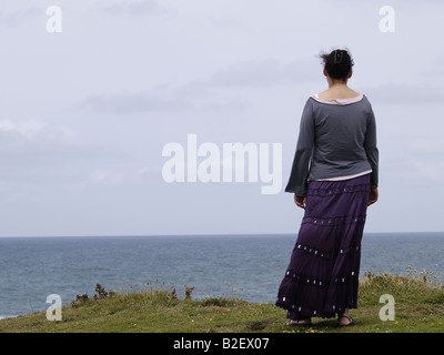 Woman standing on the cliff top looking at the view . Stock Photo