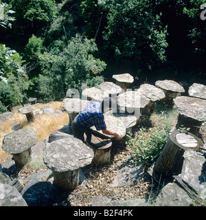 Beekeeper inspects beehives built with chestnut tree trunk and topped with Lauze stone Ardèche France Stock Photo