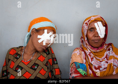 Two women sit outside a rural government health clinic in the Afar region of Ethiopia after undergoing Trachoma operations. Stock Photo