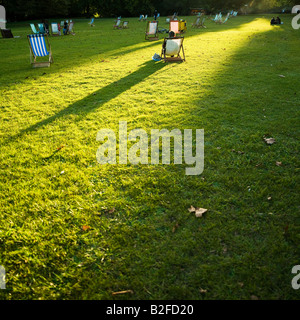 Long shadows cast by one person sitting on deck chairs in the Autumn evening sunlight of St. James park London England UK Stock Photo
