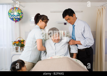 Side profile of a mid adult couple helping their mother in the hospital Stock Photo