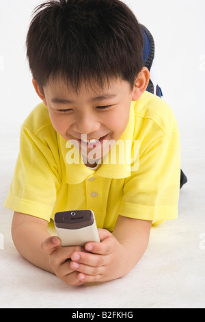 Close-up of a boy using a mobile phone and smiling Stock Photo
