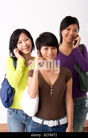 Portrait of three young women talking on mobile phones and smiling Stock Photo