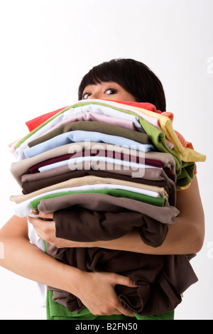 Portrait of a young woman holding a stack of clothes Stock Photo
