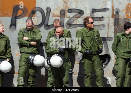 A group of German riot police stand in front of a wall spray painted with the word 'Polizei'. Stock Photo