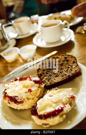 English cream tea with scones jam and clotted cream and fruit cake in bustling traditional cafe Stock Photo