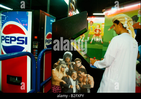 a youth wearing kandura plays arcade game in sinbads amusment centre dubai Stock Photo