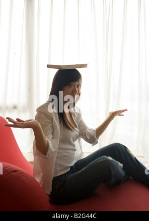 Portrait of a young woman balancing a book on her head Stock Photo
