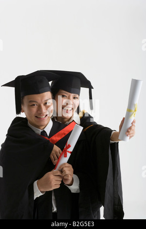 Portrait of graduate students holding diplomas and smiling in ...