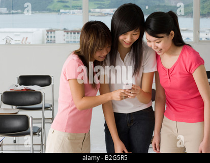 Three young women looking at a mobile phone and smiling Stock Photo